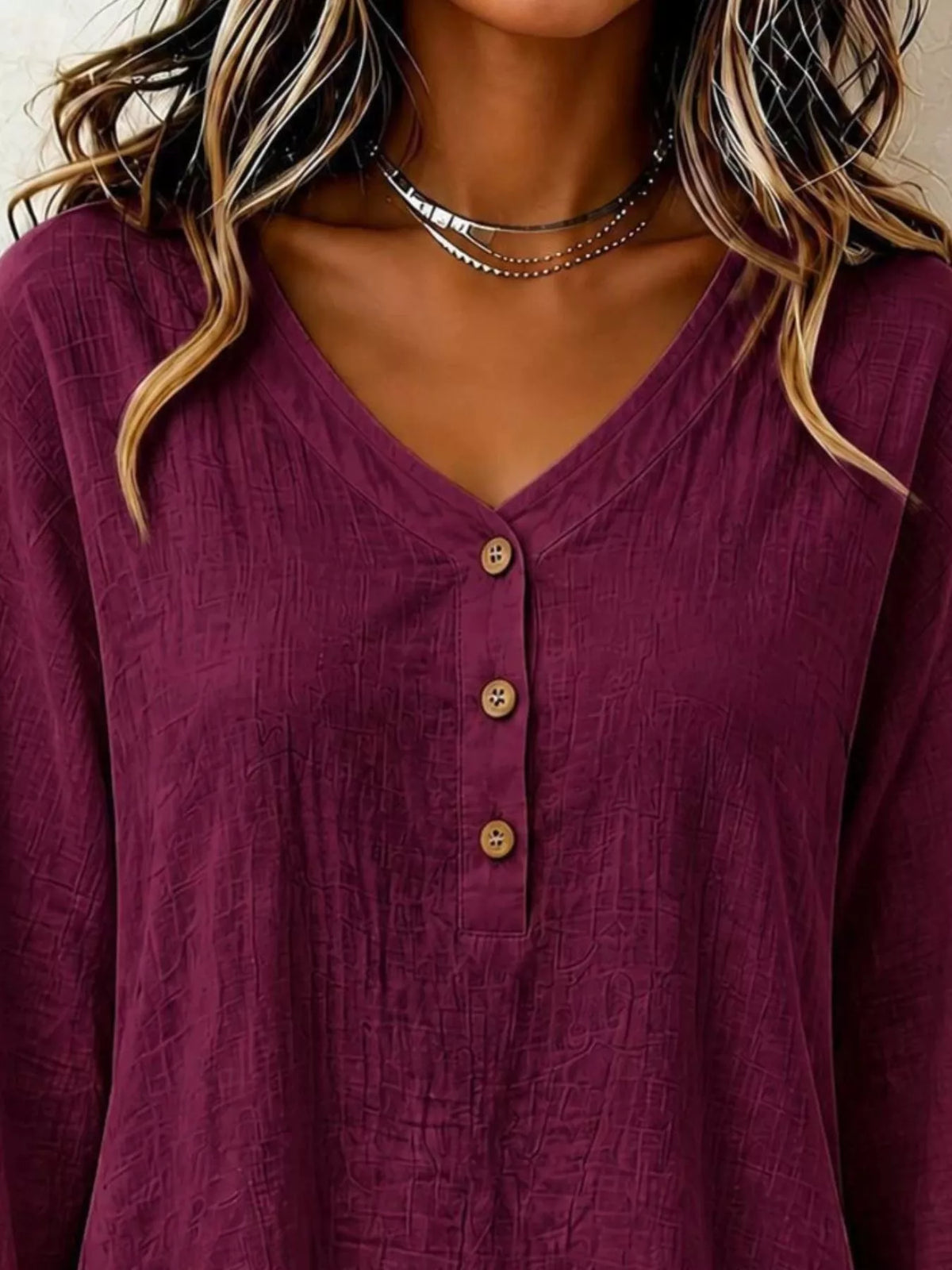 Burgundy v-neck blouse close-up with 3-button placket and long sleeves