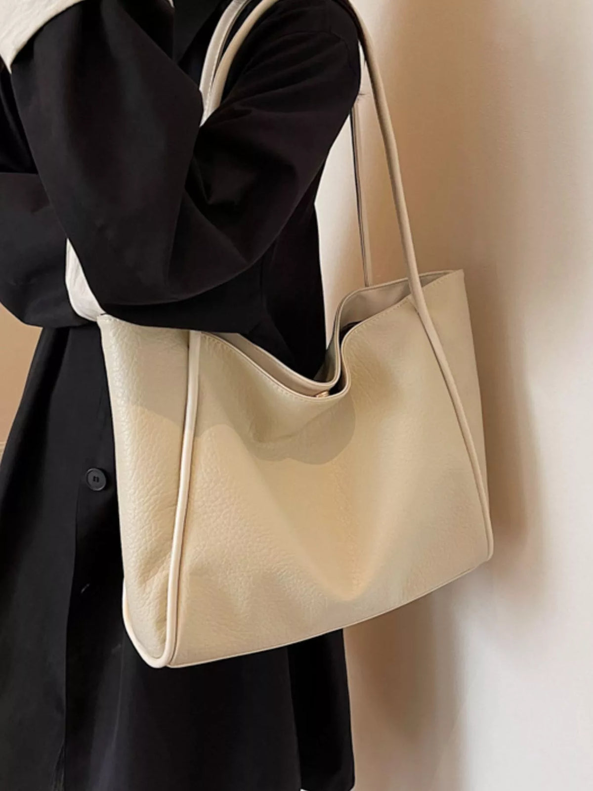 Off-white vegan leather tote bag with smooth texture and long side handles