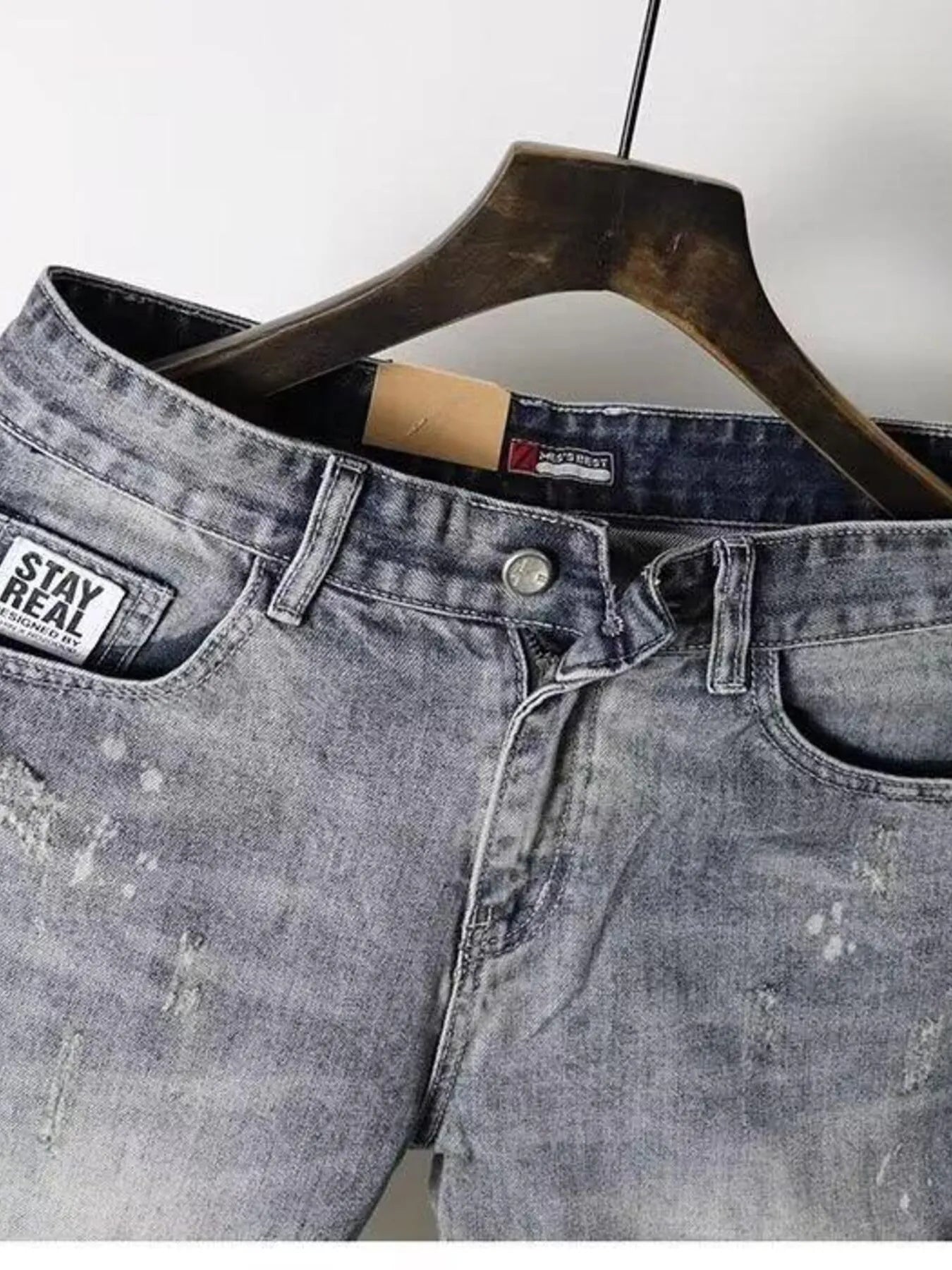 Light gray distressed denim shorts close-up of waistband with button and belt loops